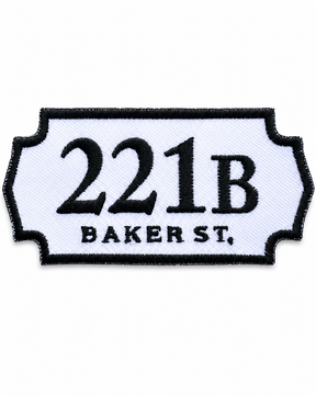 221B Baker Street embroidered patch inspired by the famous Sherlock Holmes address, featuring black lettering on a white sign-shaped badge with a black stitched border, suitable for iron-on or sew-on application.