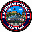 Round 80mm embroidered patch showing a stylised Edinburgh Waverley station entrance, with a castle, Saltire and clock tower behind, finished with a black border.
