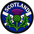 Round 80mm Scotland embroidered patch showing a large central purple and green thistle over a white Saltire on blue, with SCOTLAND lettering, finished with a black border.