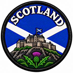 Round 80mm Scotland embroidered patch showing a stone castle on a rocky hill above a purple thistle, with a Saltire and SCOTLAND lettering, finished with a black border.