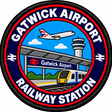 Round 80mm embroidered patch showing a passenger train at Gatwick Airport station, with an aircraft and control tower above and GATWICK AIRPORT RAILWAY STATION lettering, finished with a black border.