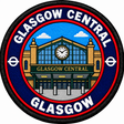 Round 80mm embroidered patch showing a stylised Glasgow Central station entrance with green framing and a central clock, finished with a black border.