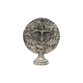 Freestanding Green Man pewter altar ornament with face surrounded by oak leaves and acorns, on display pedestal